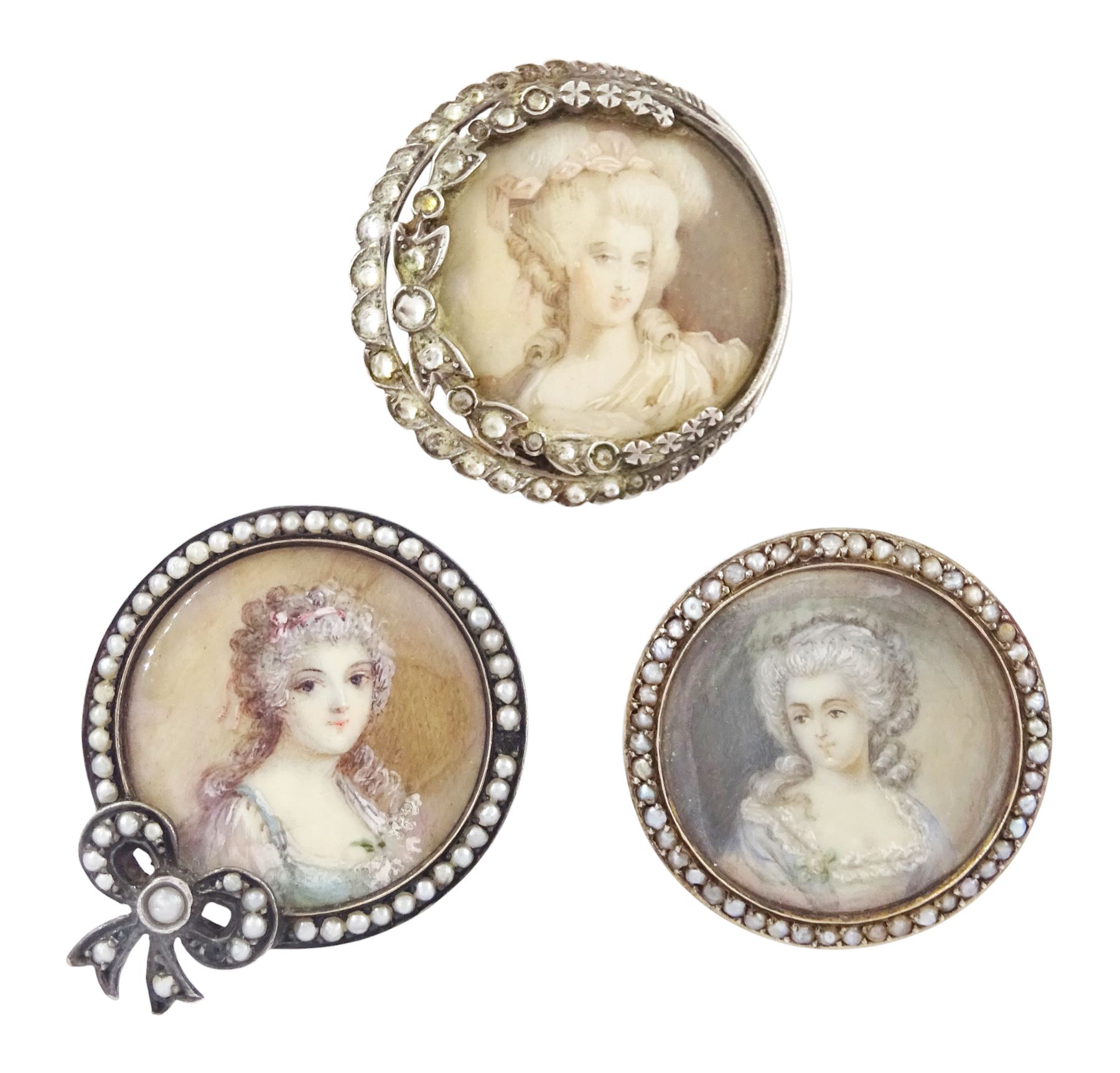Three 19th century silver portrait brooches, each set with miniatures of women in 18th century dress on ivory, two with seed pearl surrounds and the other within a foliate paste set surround. This lot has been registered for sale under Section 10 of the APHA Ivory Act