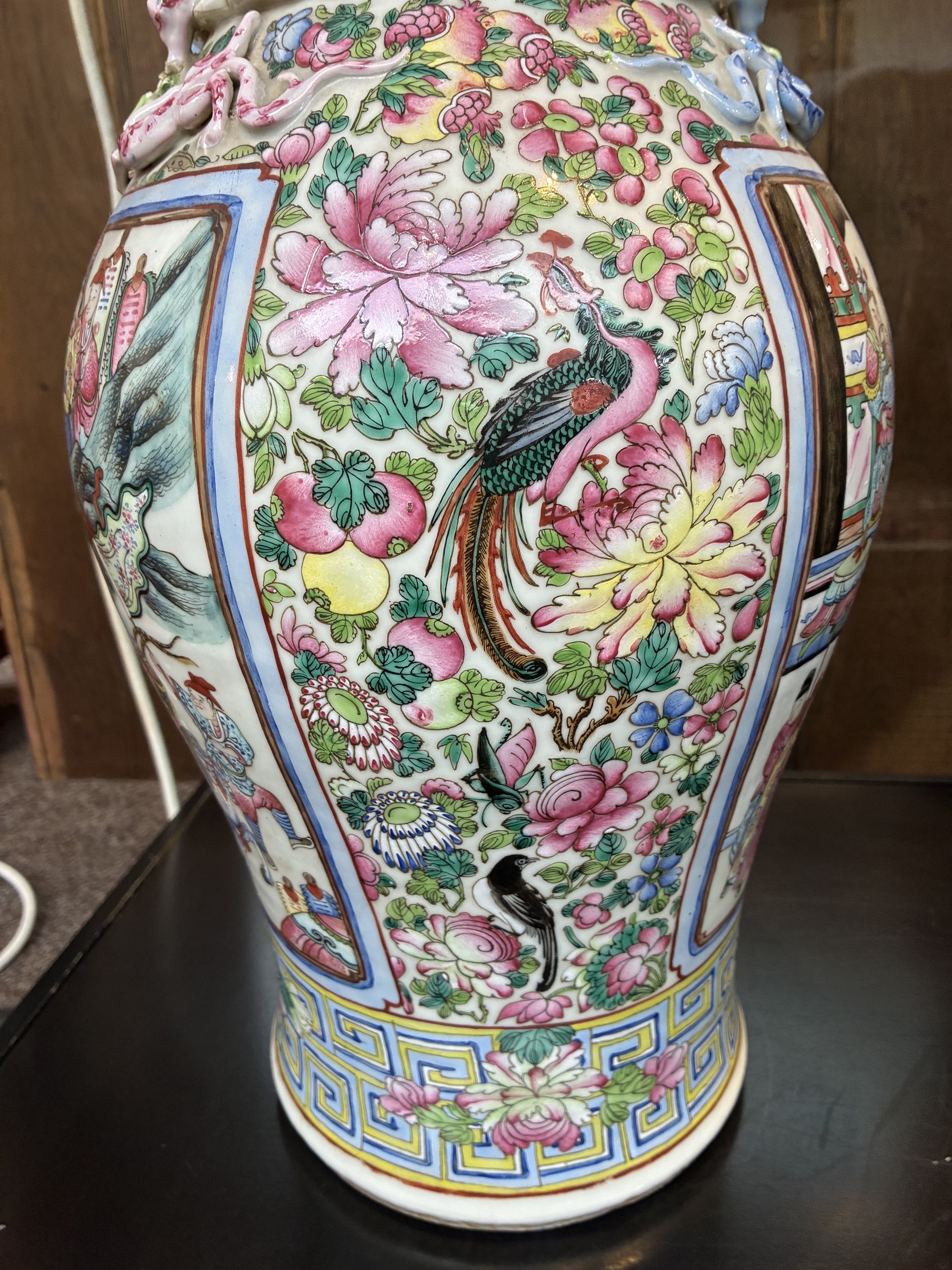 Large pair of 19th century Cantonese famille rose vases, each painted with various courtly scenes, including a display of warriors fighting on horseback before an official and his attendants, double Buddhist lion handles and applied at the shoulders with chilong, the lower band painted with Greek key motif, H58cm (2)