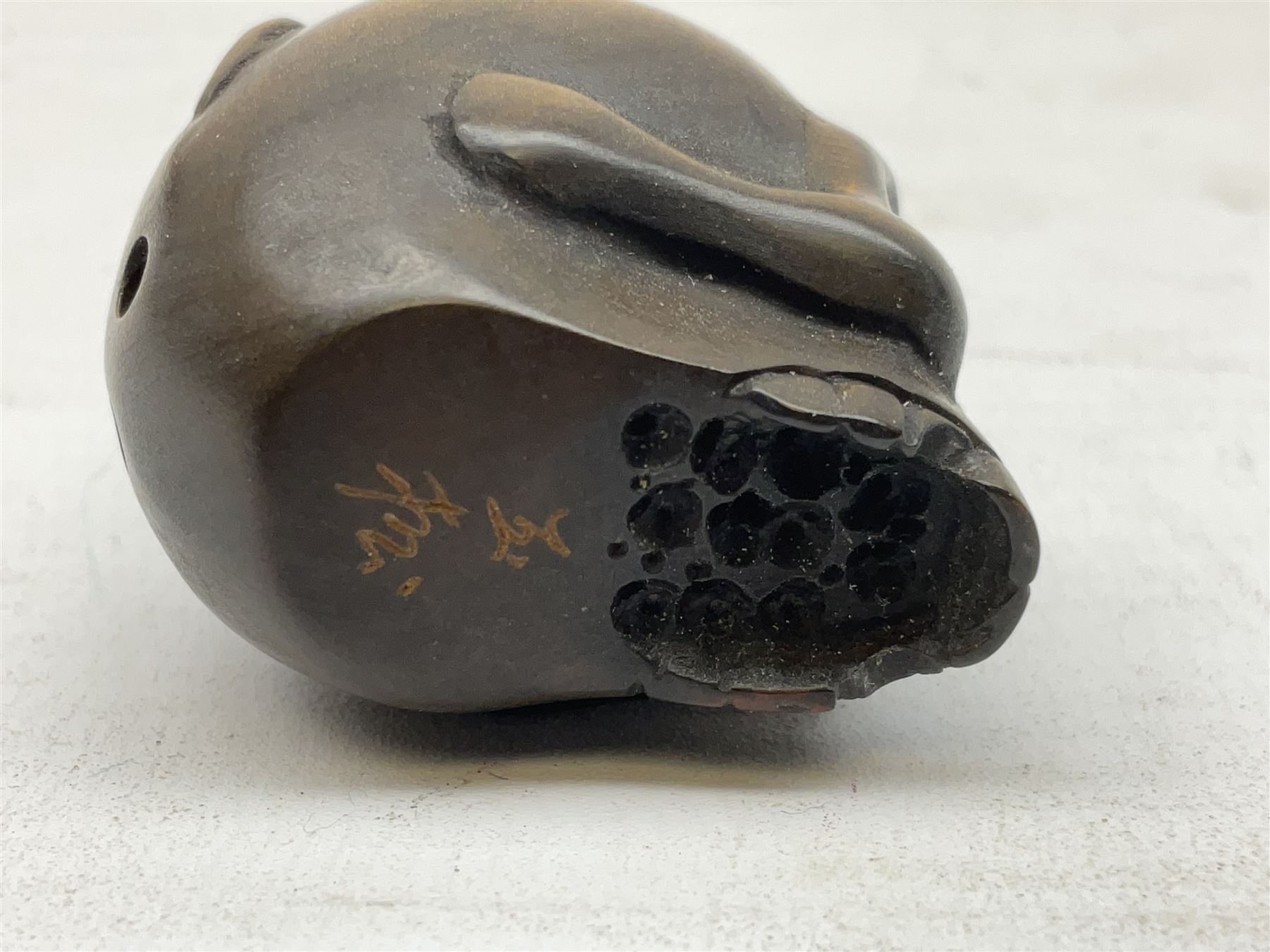 Netsuke in the form of a rat sitting on a skull, signed to the base