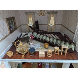 Two modern three storey dolls houses, each painted green with decorated interiors, both upon a single white wooden base, together with a large collection of dolls house furniture, accessories and figures 