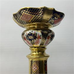 Pair of modern Royal Crown Derby Old Imari 1128 pattern candlesticks, each with shaped drip tray affixed to squat socket, upon spreading stem and canted square base with gilt dolphin edges, with printed marks beneath including Roman numeral year cypher for 2003, H26.5cm, with original boxes