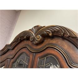 Kevin Charles American walnut display cabinet, illuminated interior, shell carved pediment above four bevel edge doors enclosing six glazed shelves above one central long drawer flanked by two short drawers, above three cupboards, carved bracket supports 