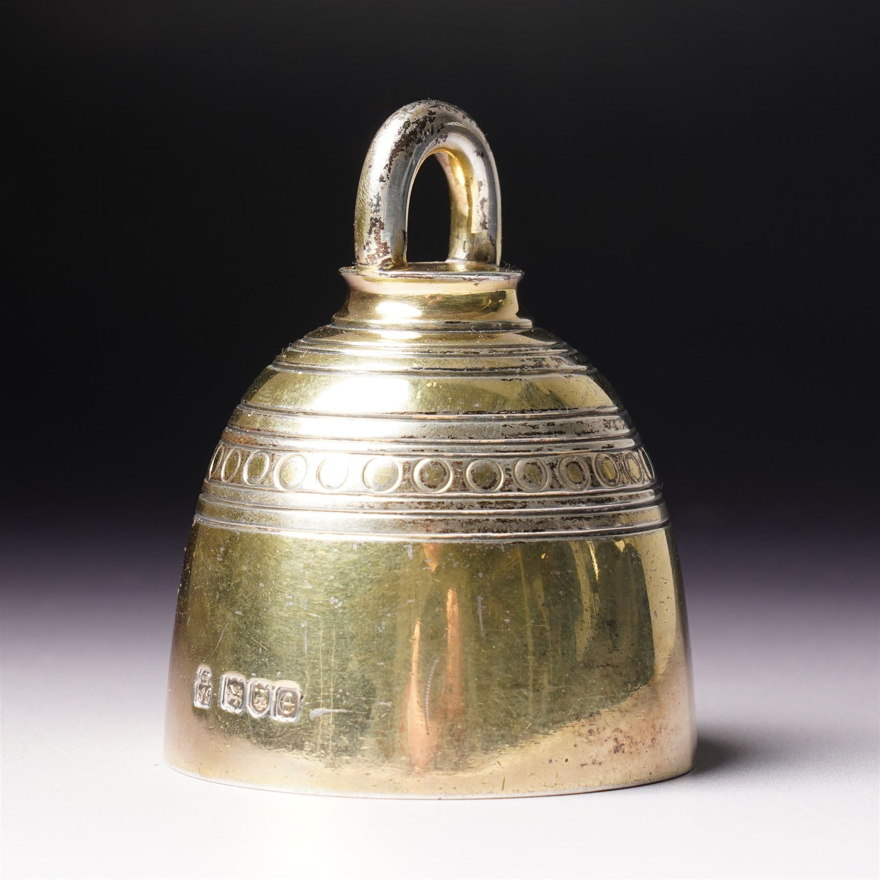 Late Victorian silver gilt table bell with reeded and roundel decoration and loop handle, bell and clapper both hallmarked H7cm London 1900 Maker R & S Garrard & Co