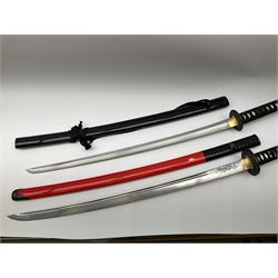 Reproduction Japanese sword daisho of katana and wakisashi with matching tanto; together with another reproduction katana; all with simulated fish skin grip and lacquered saya (4)