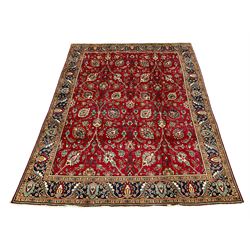 Large Persian Tabriz carpet, red ground field decorated with interlacing branch and trailing foliage, stylised flower head and plant motifs, the border decorated with stylised foliage motifs