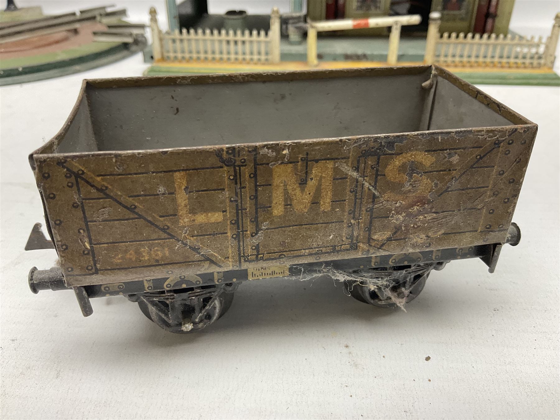 '0' gauge - Bing tin-plate two-storey double sided station with open walk-through to one end, rail side canopy, hinged doors and removable roof giving access to clock illumination L35cm; Bing hand-cranked turntable and open wagon; Marklin tin-plate level crossing barrier and Newspaper vendor's tin-plate four-wheel hand cart (5)