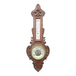 Victorian carved oak aneroid barometer, the foliate crest above a glazed thermometer, with...