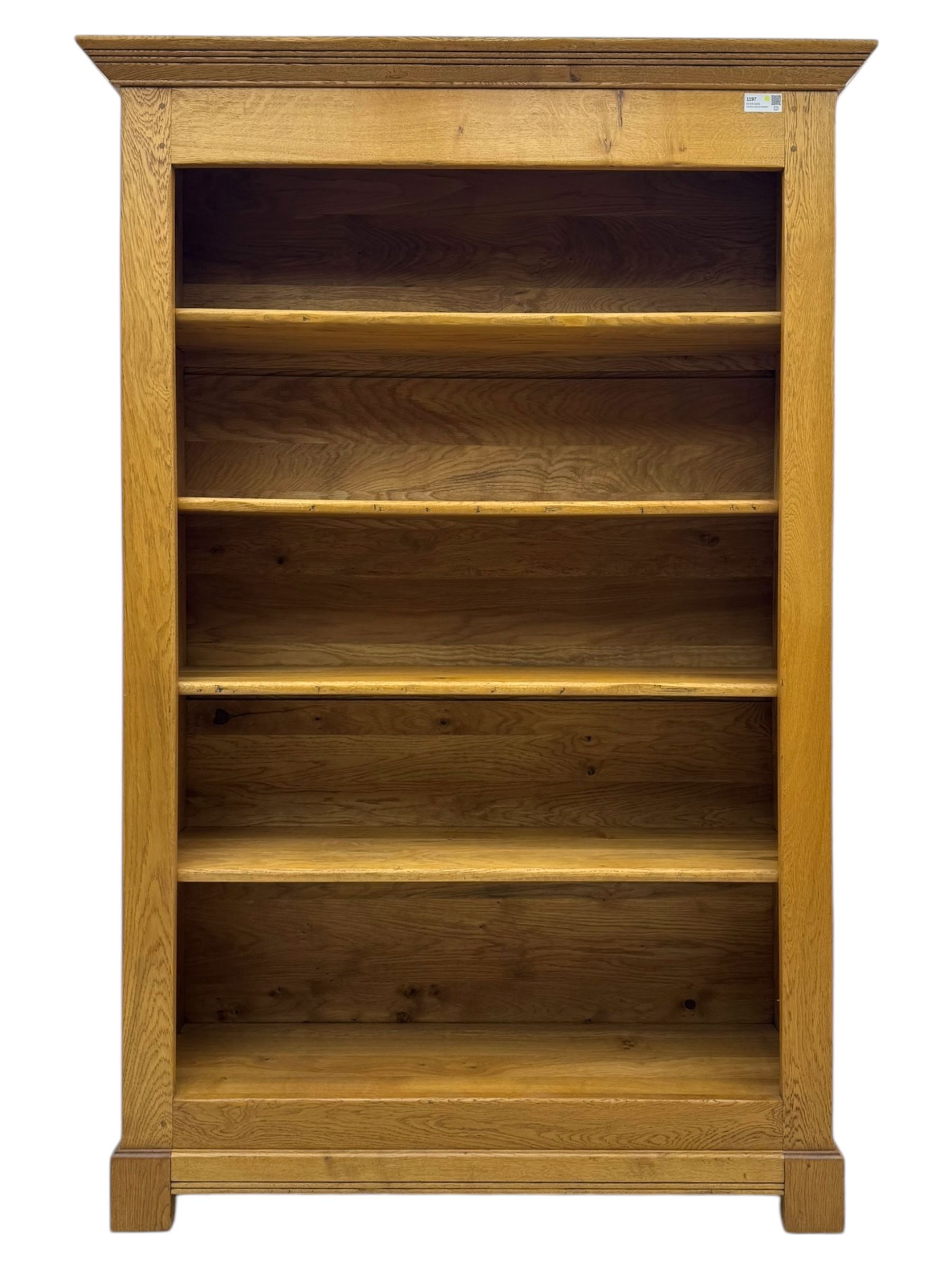 Contemporary French provincial design oak open bookcase, with projecting moulded cornice above a boarded back, fitted with four adjustable shelves, on bracketed plinth base
