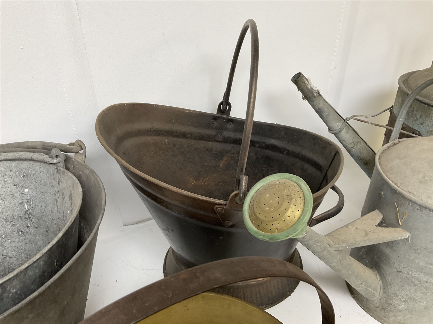 Two vintage galvanised watering cans, three galvanised buckets and a brass jam pan