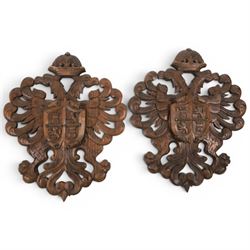Carved wooden wall plaque, decorated with foliate scrolls, with two reproduction swords attached, together with five other wooden plaques with foliate scrolls and shields