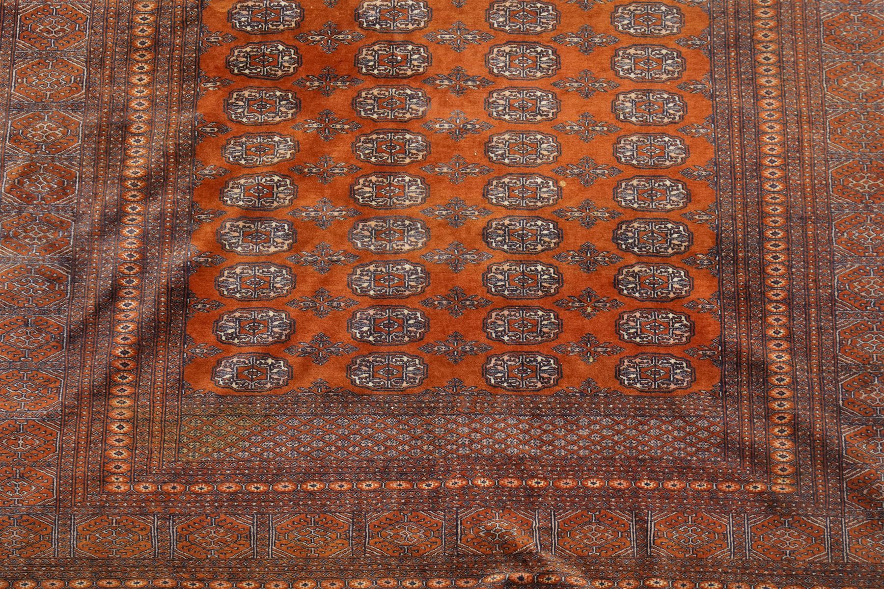 Bokhara hand-knotted carpet, terracotta ground with repeating rows of Tekke guls and geometric motifs, enclosed by multiple geometric borders, with silk highlights, fringed ends