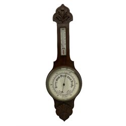 An English carved oak cased aneroid barometer with an 8'' porcelain dial, measuring barometric pressure from 26 to 31.9 inches, weather predictions written in gothic capitals and lower-case script, with a steel indicating hand and brass recording hand within a chrome bezel with a flat bevelled glass, with a spirit thermometer recording the temperature in degrees Fahrenheit and Celsius.



