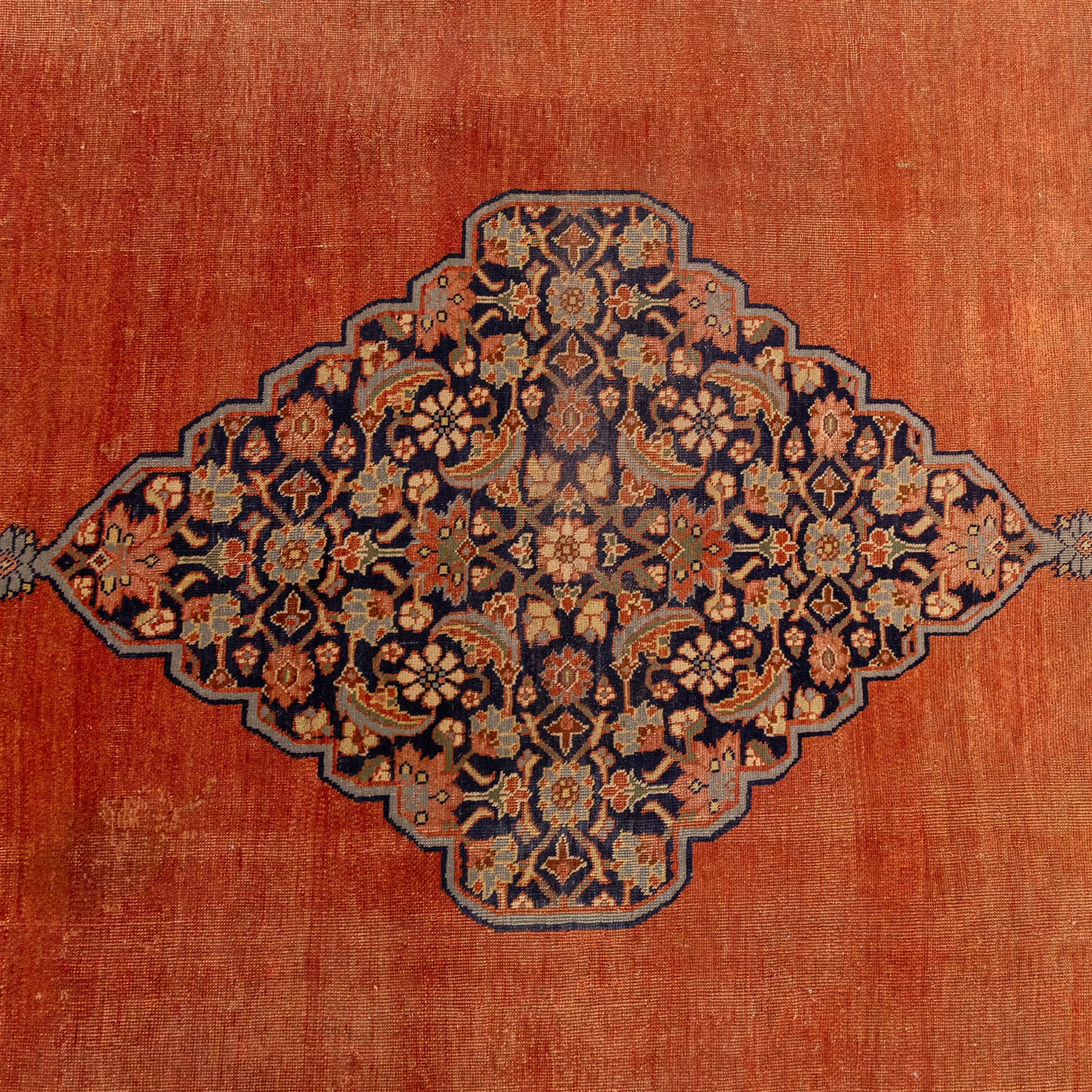 North West Persian Tabriz hand-knotted carpet, salmon field with central elongated lozenge medallion intricately filled with scrolling arabesques and palmettes, framed by stylized corner spandrels within a broad indigo main border  of bold palmettes and floral vinery between multiple guard stripes, rendered in tones of terracotta, sage green, and soft ivory, with cotton fringe ends 