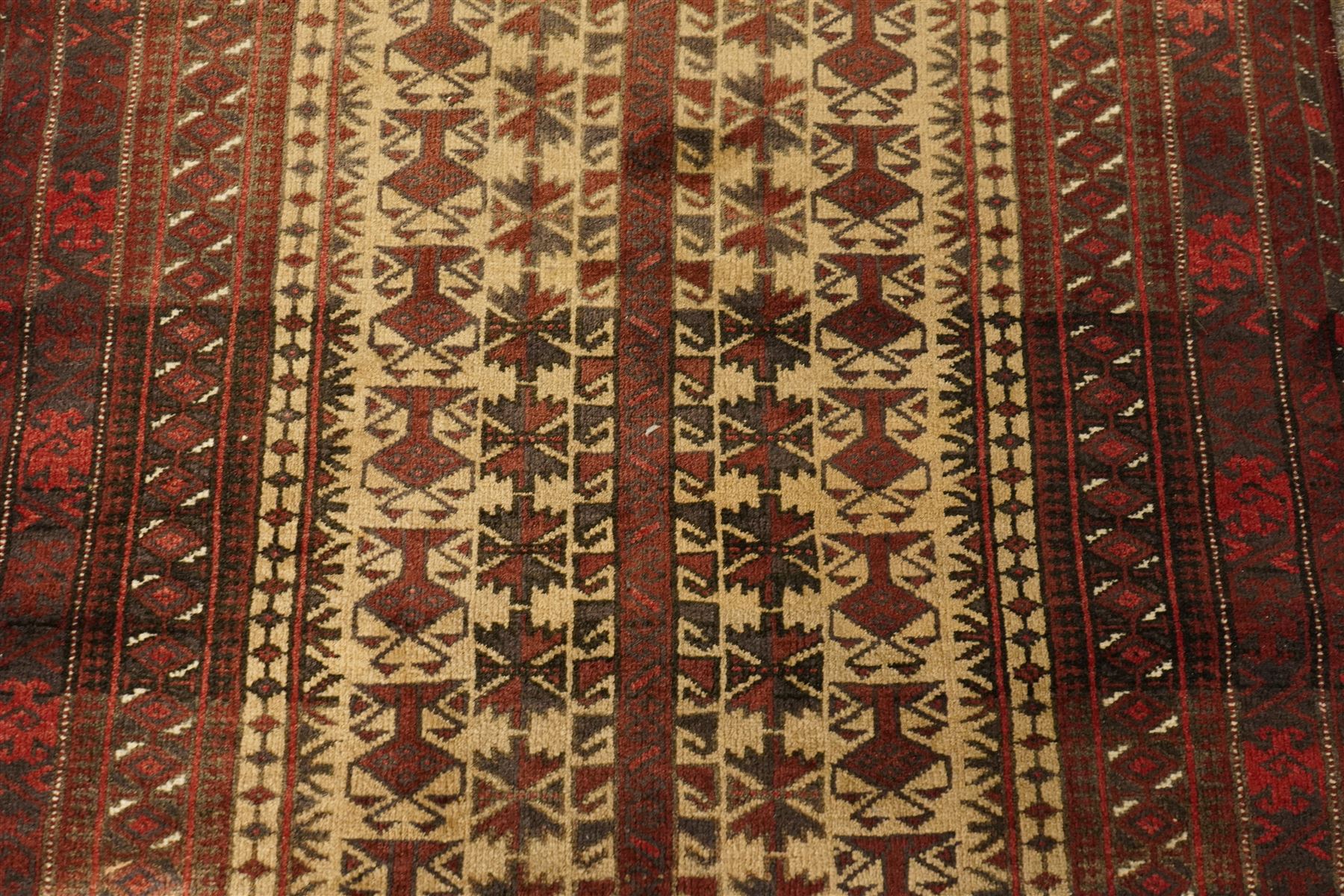 Two hand-knotted rugs, comprising Persian runner and Turkoman prayer rug, Persian hand-knotted runner, red and dark navy ground with four diamond medallions and geometric motifs, enclosed by multicoloured geometric border, striped kilim ends with fringes, H244cm, W58cm; Turkoman hand-knotted prayer rug, ivory mihrab field decorated with repeating stylised geometric motifs, enclosed by multiple geometric borders in madder red and brown, with fringed ends, H150cm, W93cm