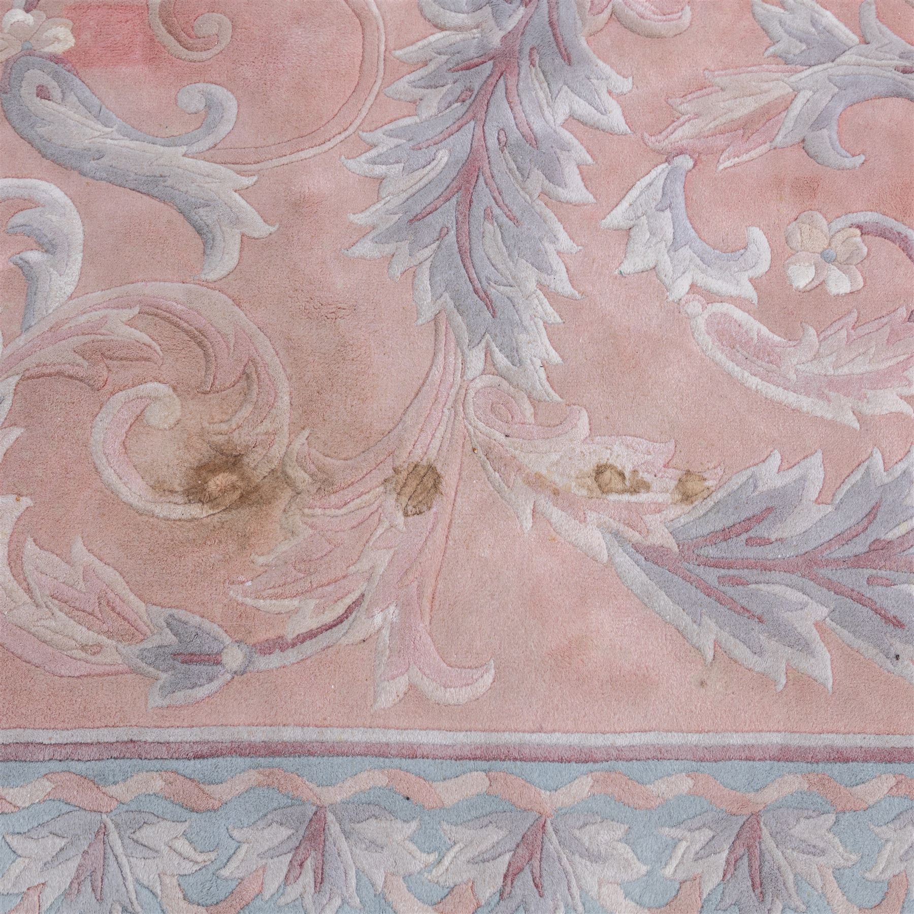 Large late 20th century Aubusson style wool carpet, peach and pastel toned field with central floral medallion enclosing scrolling acanthus and and foliate sprays, surrounding field decorated with further stylized foliage and and floral ornament, within shaped reserves and indigo corner spandrels, enclosed by narrow guard border, cotton fringe ends
