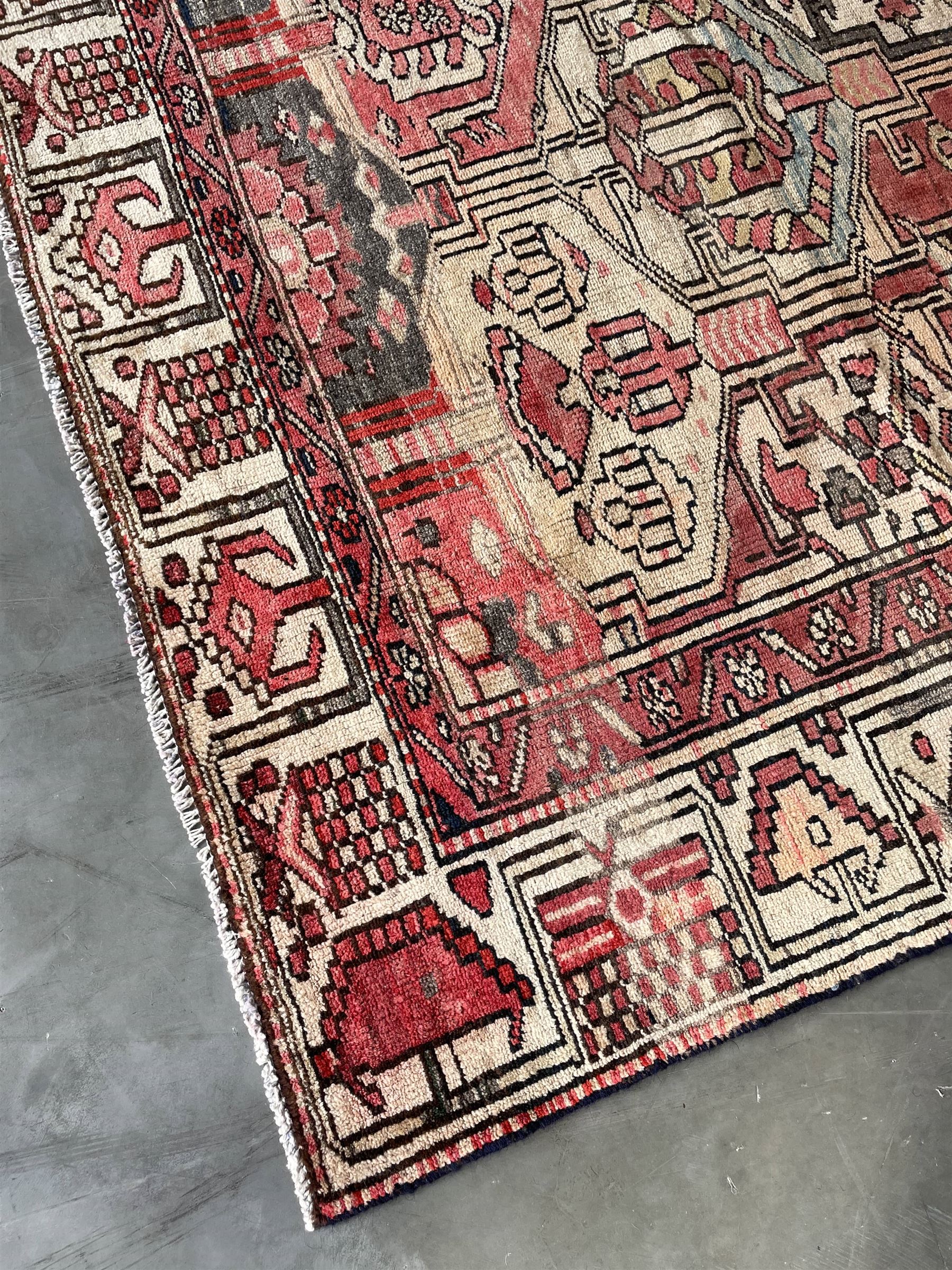 Persian Heriz red and pale ground rug, depicting multiple shaped panels with stylised motifs and designs, geometric patterned border