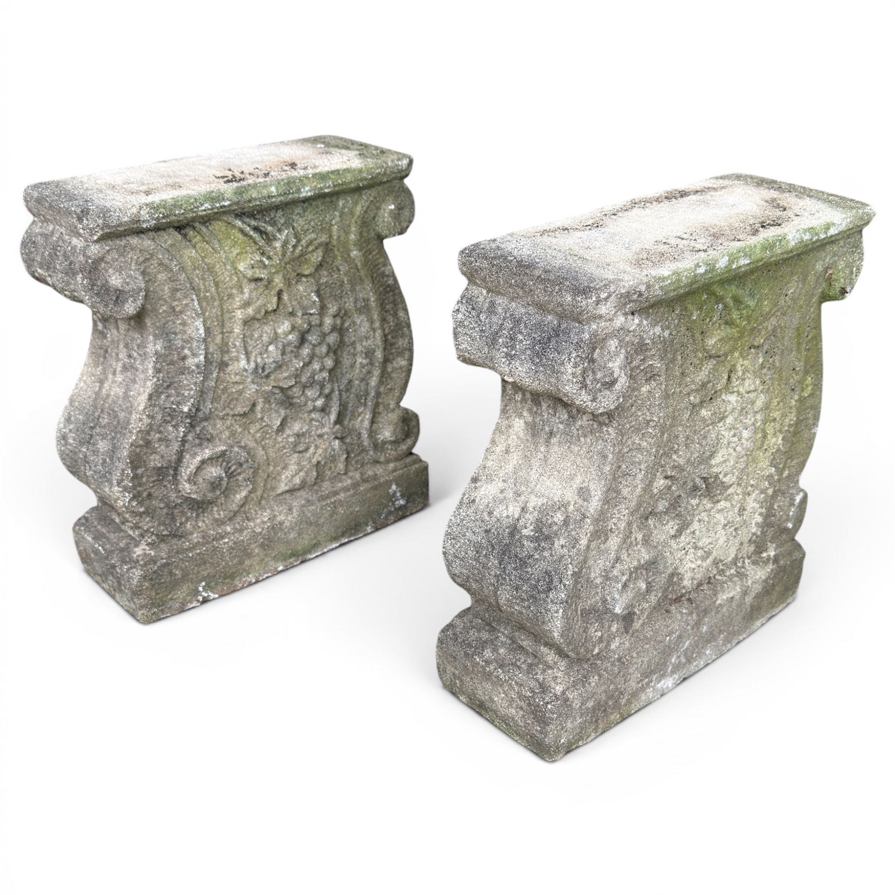 Weathered cast stone three piece bench, the rectangular seat with moulded edge, raised on Neoclassical style end supports with S-scrolls and fruiting grapevines, on rectangular bases, along with two extra legs