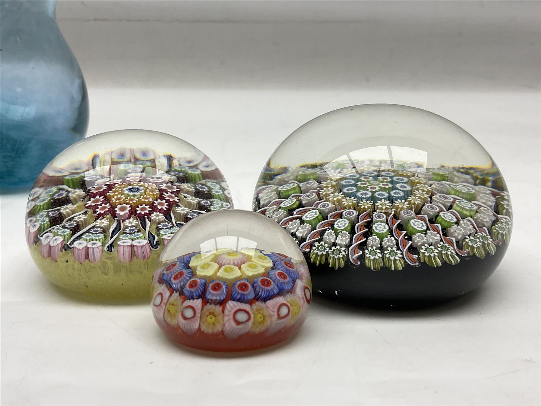 Three millefiori paperweights, together with a green glass dump paperweight with air bubble inclusions, Caithness Daisy and Cauldron paperweights and two small Caithness glass vases, tallest H9cm