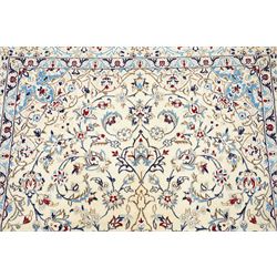 Central Persian Nain hand-knotted rug, ivory field with central medallion in tones of indigo and blue, issuing vinery, palmettes and floral sprays with conforming spandrels, dark blue main border of floral vinery and stylized palmettes, framed by multiple guard borders, with cotton fringe ends 