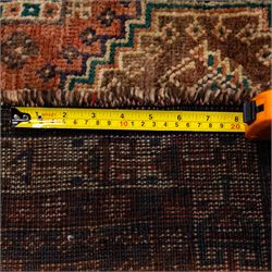 South West Persian Qashqai hand-knotted rug, salmon pink field with central stepped geometric medallion with issuing stylized tree and floral motifs, surrounded by angular devices, with indigo spandrels and multiple geometric borders, fringe ends 