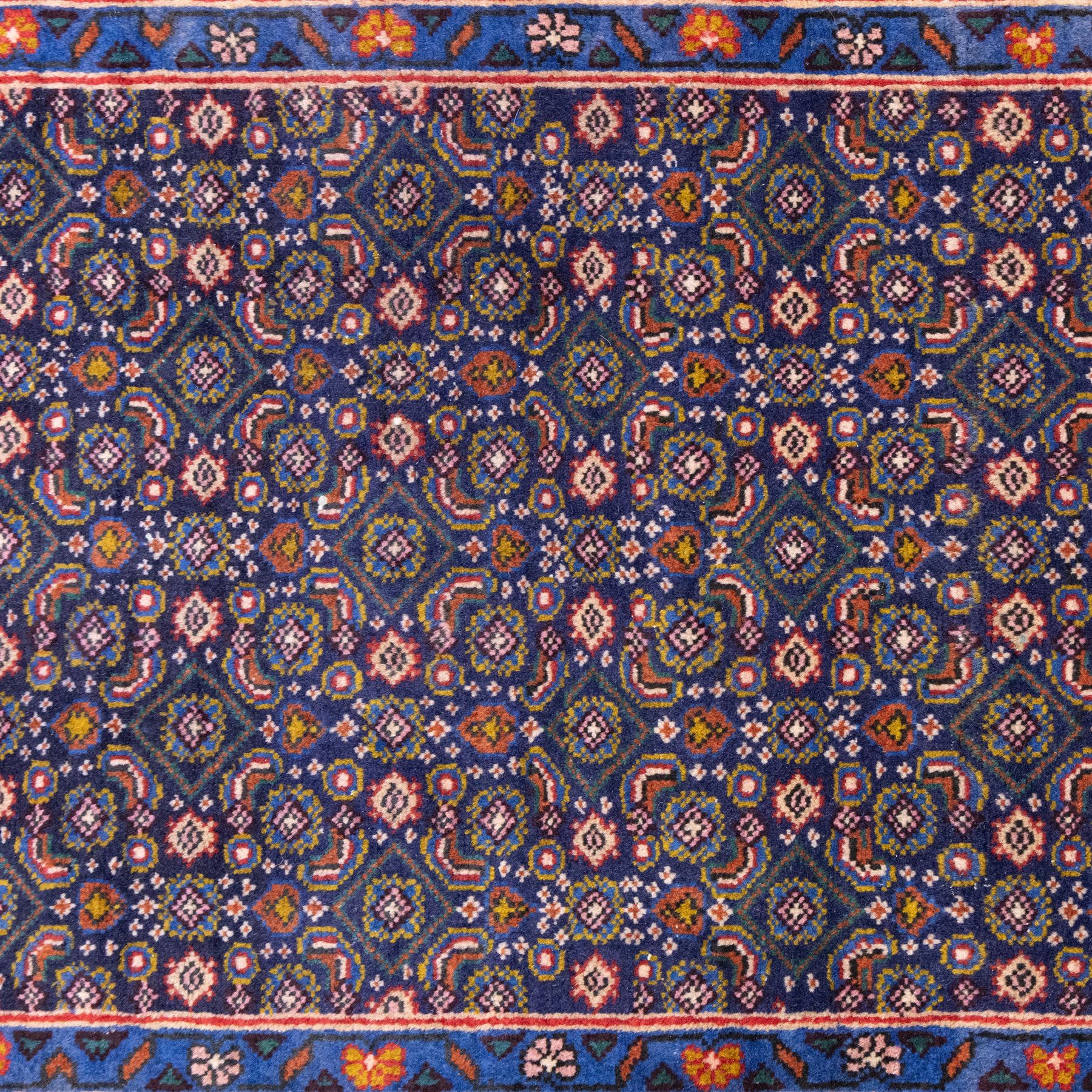 North West Persian Bidjar hand-knotted runner, decorated with an all-over herati pattern on a deep indigo ground, the field is filled with a repeating diamond and rosette motifs, interspersed with stylized leaves and floral elements, framed by a border on an ochre ground flanked by contrasting guard borders, with cotton fringe ends 