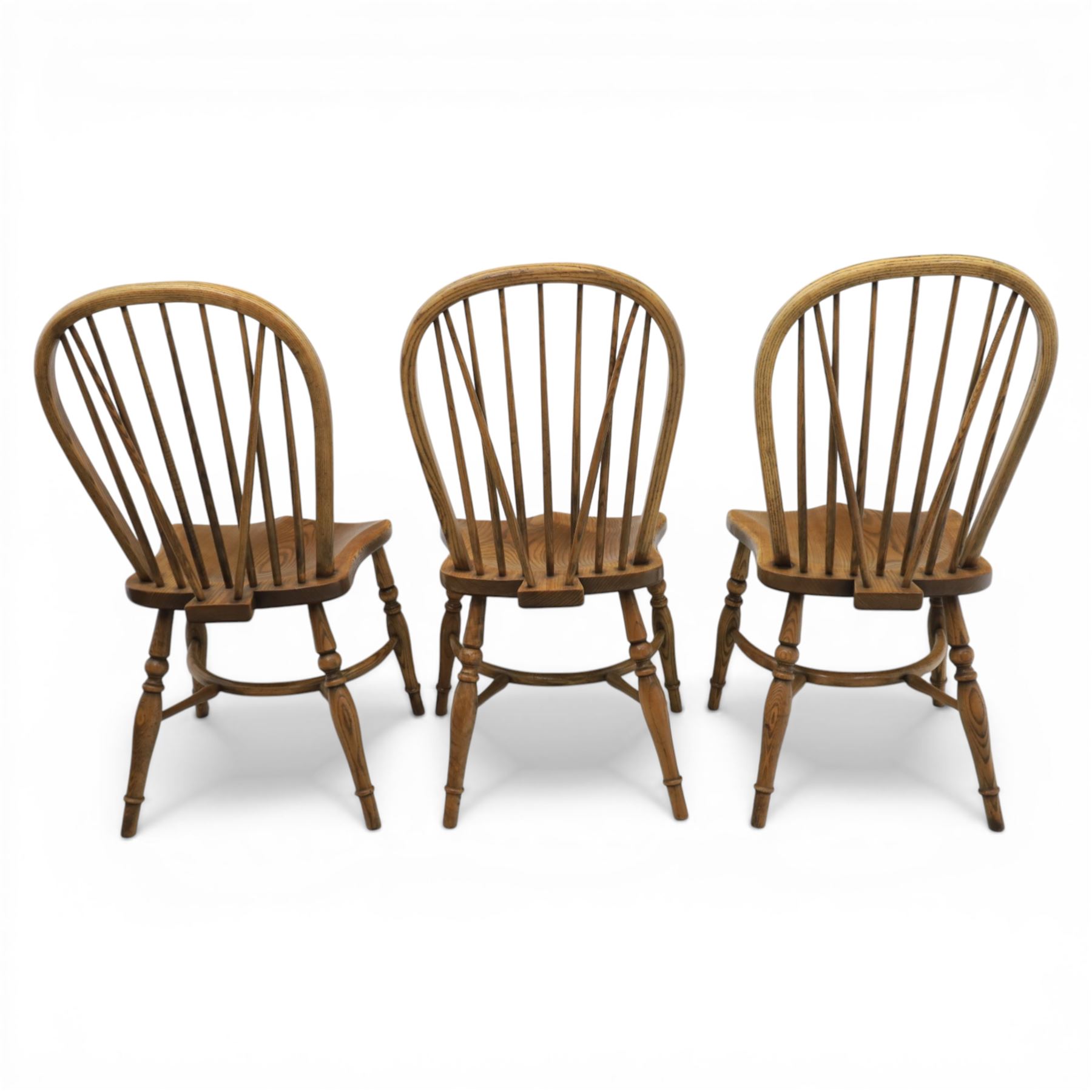 Traditional elm and beech Windsor dining chairs, each with hoop back and turned spindles over a shaped solid seat fitted with loose floral upholstered cushions, raised on turned tapering supports united by crinoline stretchers
