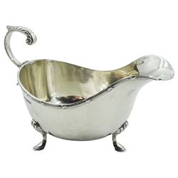 1930's silver sauce boat, of typical form with ribbon wrapped reeded border to rim, flying acanthus capped scroll handle, upon three hoof feet, hallmarked Walker & Hall, Sheffield 1934, approximate weight 3.95 ozt (123 grams)