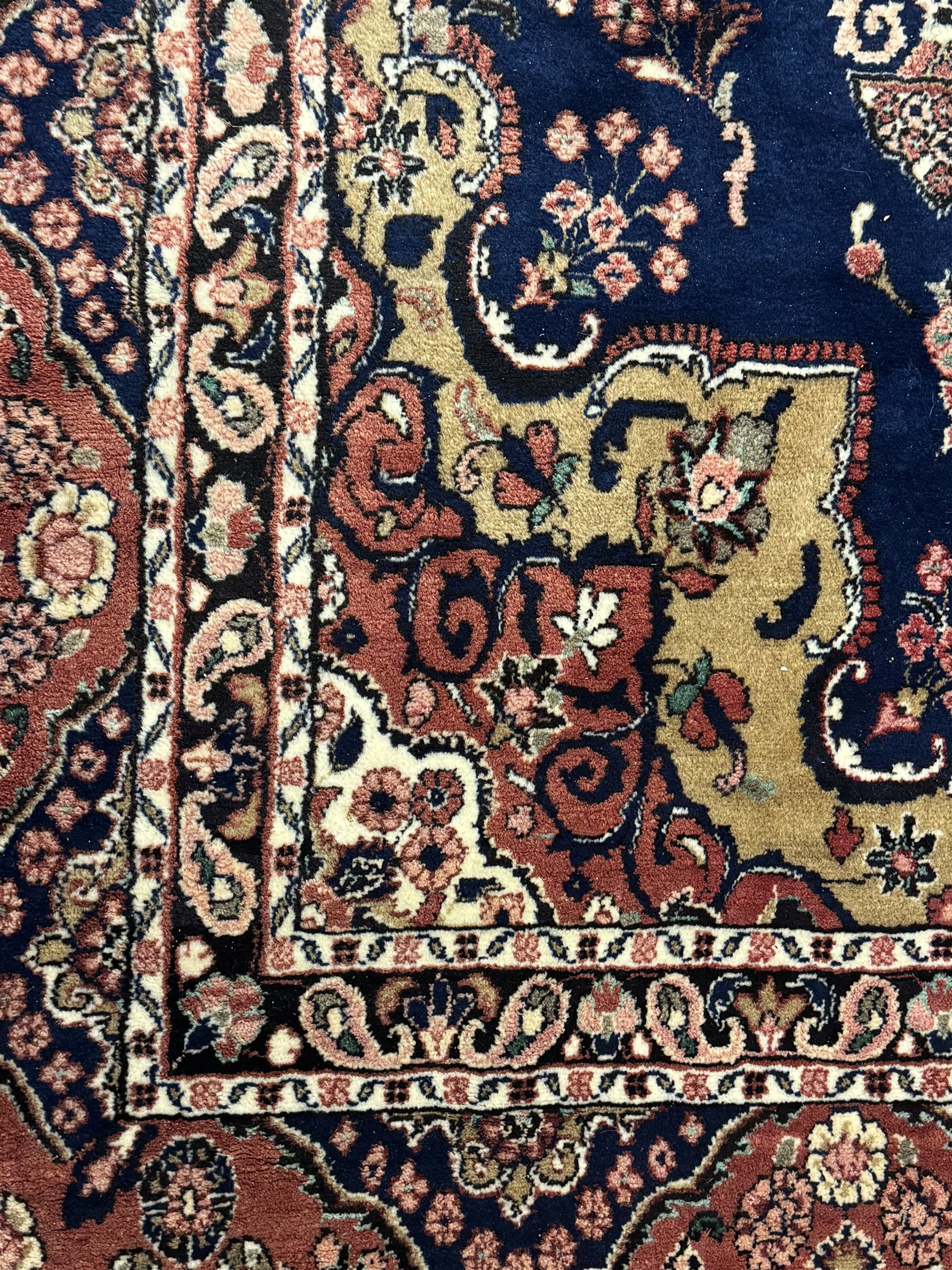 Persian Herati design indigo and red ground carpet, decorated with floral motifs, arched border