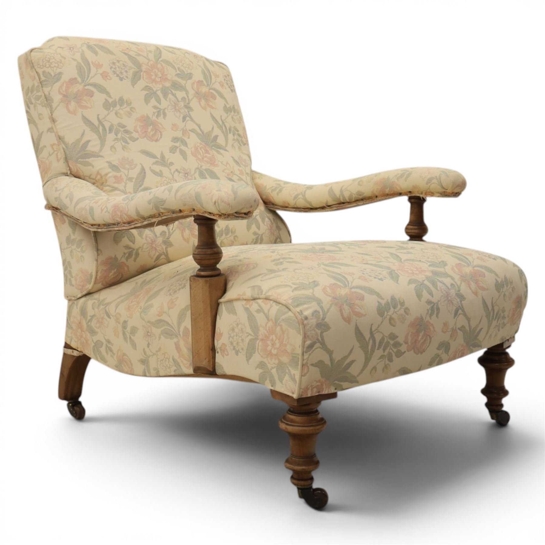Victorian mahogany framed deep seat low drawing room chair, upholstered in beige floral fabric, on turned supports terminating in castors