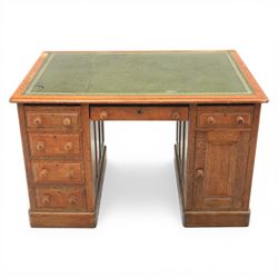 20th century oak compact pedestal desk, tooled green leather inset top, above a single frieze drawer, with a bank of four graduated drawers and a drawer and cupboard, panelled sides raised on castors