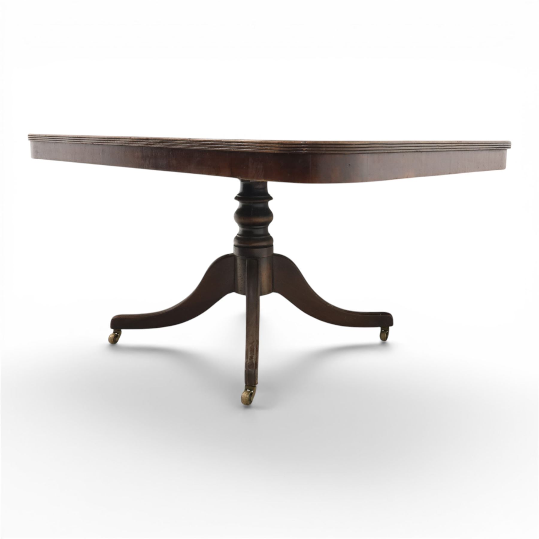 Regency mahogany tilt-top dining table, crossbanded rounded rectangular top, raised on a splayed base, terminating in brass castors