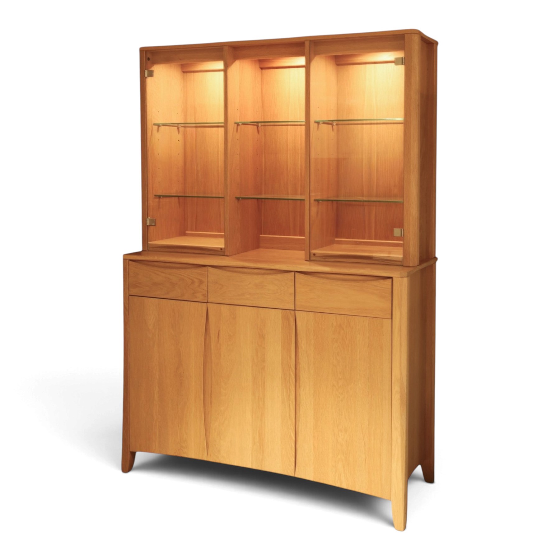 Ercol - 'Artisan' light oak dresser, upper section with cantered corners, with central open area fitted with adjustable glass shelves, flanked by twin glazed cabinets with further adjustable glass shelving, the lower section with three shorts drawers with recessed handles, above three cupboard doors with recessed handles enclosing adjustable wooden shelves, raised on short tapering supports 