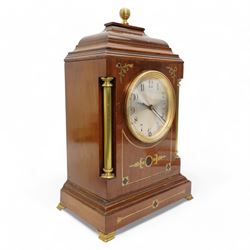 Edwardian- Early 20th century 8-day mahogany mantle clock, with a stepped pediment and brass finial, recessed brass pilasters and brass inlay to the front with a conforming plinth raised on bracket feet, silvered dial with Arabic numerals and steel spade hands within a glazed brass bezel, single train timepiece movement with pendulum and key.
