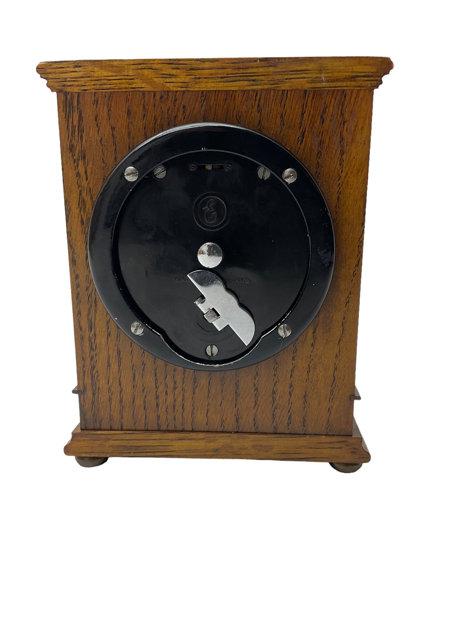 Elliot - oak cased 1950’s 8-day timepiece mantle clock, with a balance wheel movement wound and set from the rear, flat topped case with a carved panel raised on bun feet, square brass dial, silver chapter ring, spandrels and  decoratively engraved dial centre inscribed “Bracher & Sydenham, Reading”