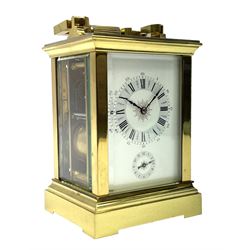 Early 20th century brass and bevelled glass repeater carriage clock with alarm, the angular and cylindrical ribbed handle and repeater button over stepped cavetto cornice, white enamel Roman dial with Arabic subsidiary alarm set dial, twin train eight day movement striking the hours and half on coil, separate alarm mechanism train, stepped moulded and plain faced base, with leather travelling case