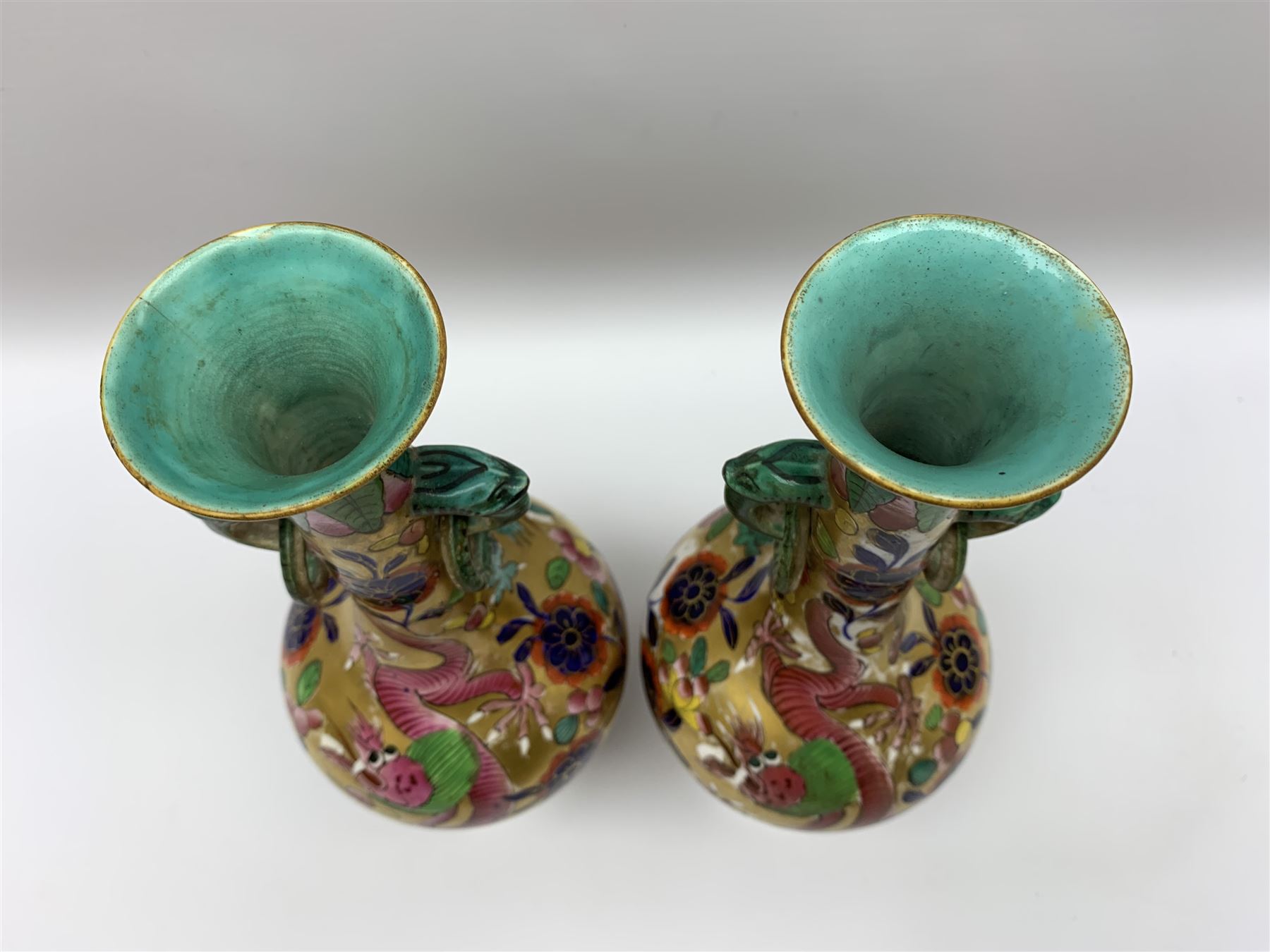 Pair of early 19th century Miles Mason vases, the baluster bodies with tall slender necks supporting twin stylised trunk handles with rings, decorated with Chinese dragons, butterflies, and blossoming flowers against a gilt ground, with spurious Chinese marks beneath in iron red, H27.5cm