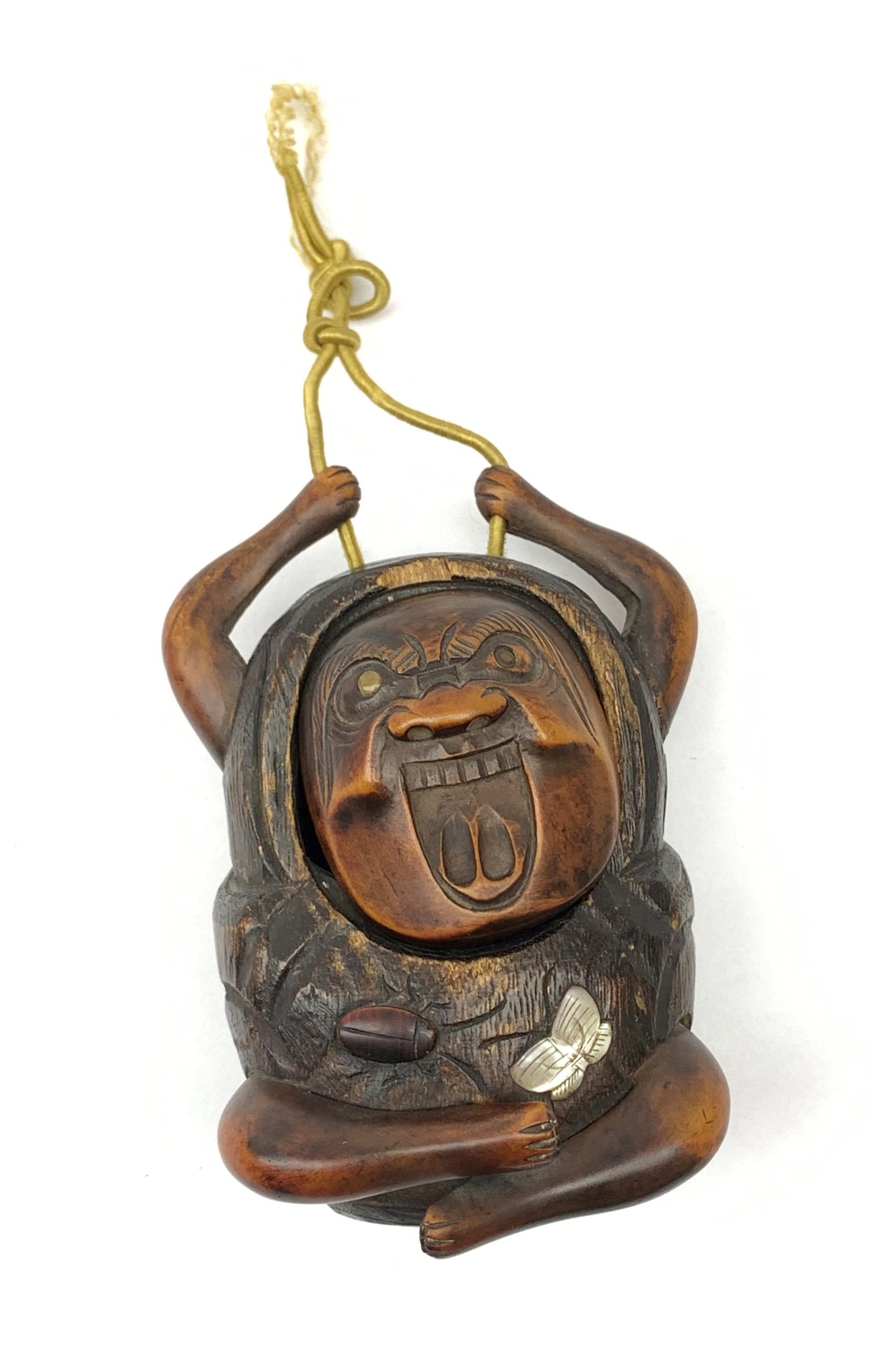 A Japanese carved soft wood inro, modelled as a streching and yawning figure, possibly Daruma, detailed with insect, inset mother of pearl butterfly, and glass eyes, H10cm. 
