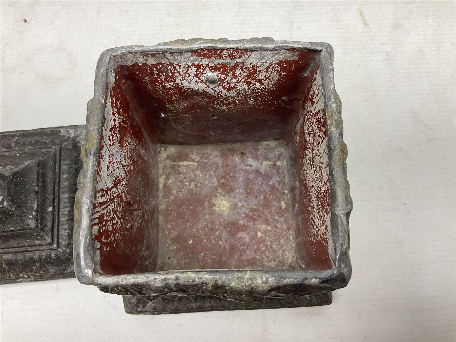 19th century lead tobacco box, the body of square form decorated with panels of courting couples in relief supporting stepped tapering lid with figural male head finial, H18.5cm