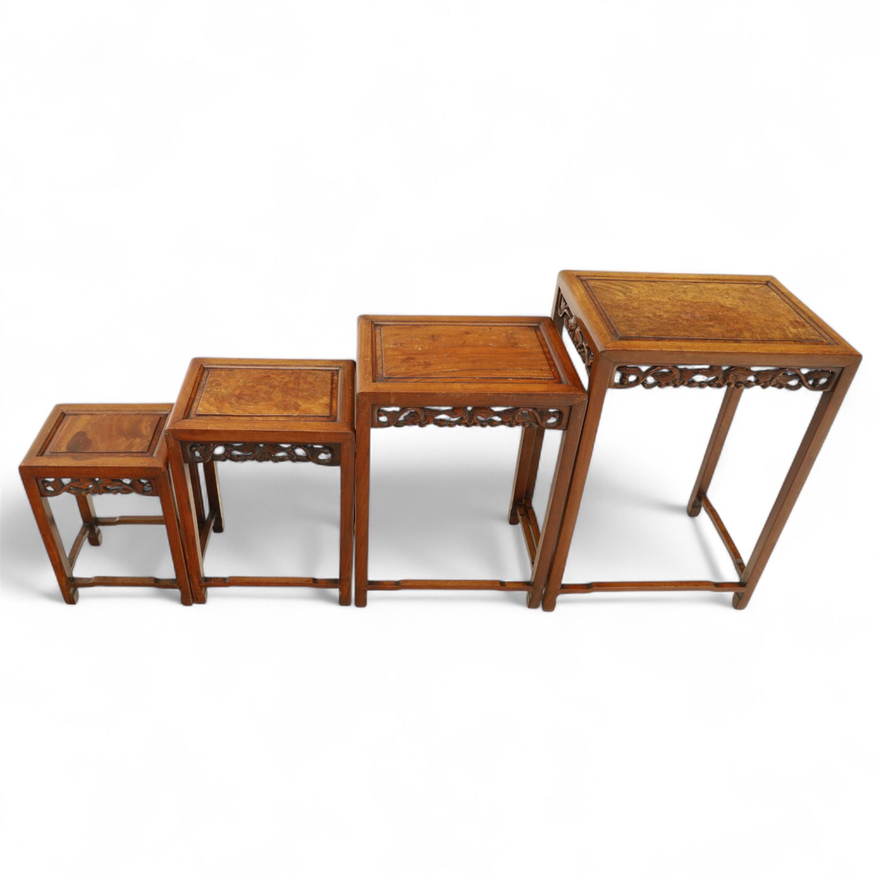 Early 20th century Chinese style hardwood quartetto nest of tables, each with panelled top and carved and pierced vine motif frieze, on square legs united by straight stretchers
