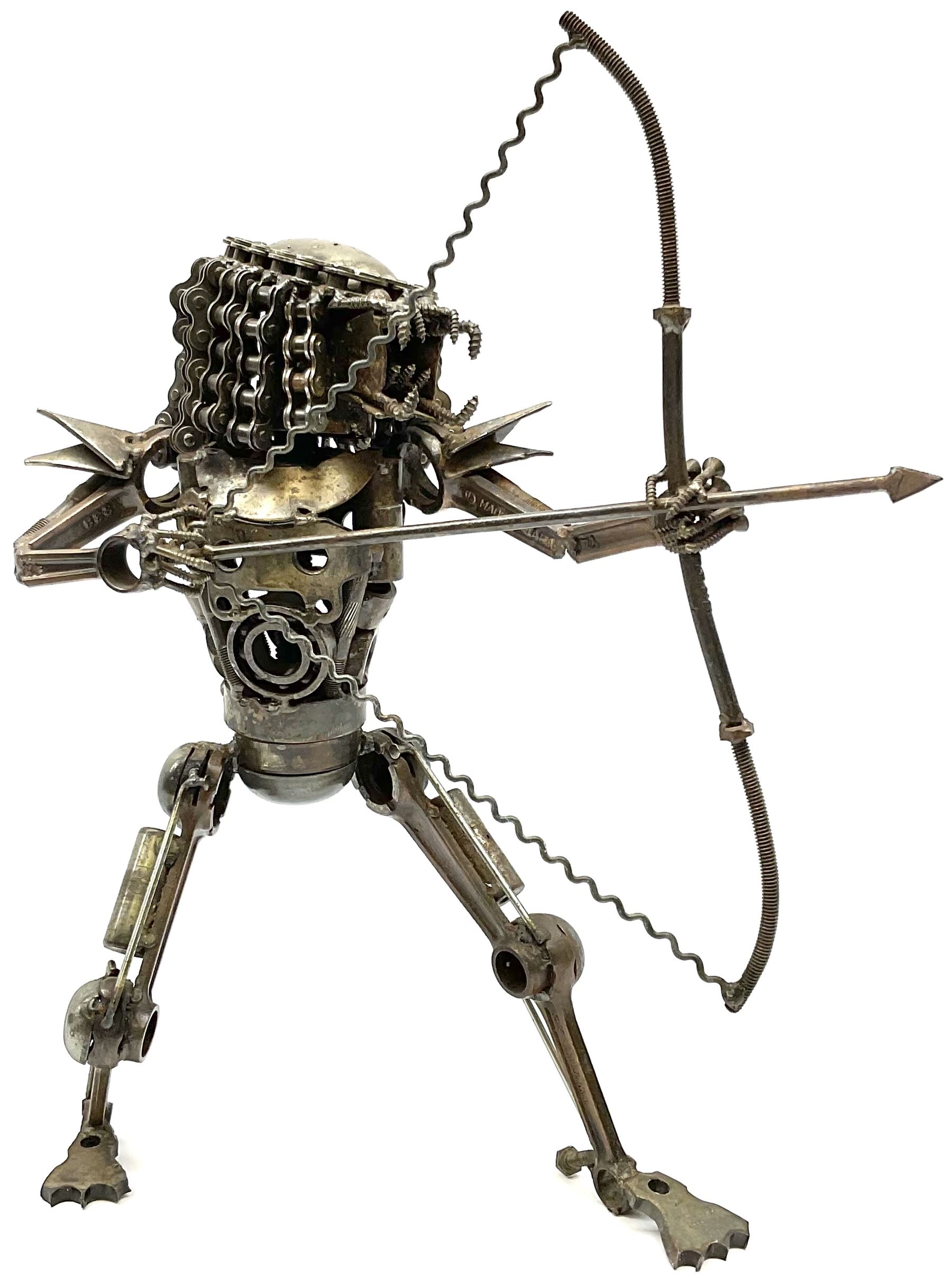 Predator metal sculpture, made with scrap metal, with articulated body, bike chain hair, and bow and arrow, H45cm