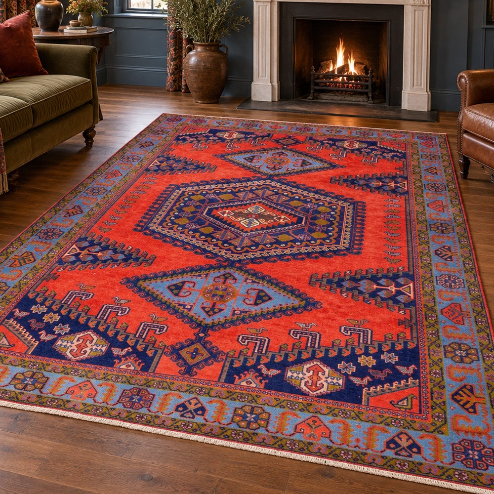 West Persian Veis hand-knotted rug, coral red field decorated with a series of bold geometric lozenge medallions in shades of indigo and sky blue surrounded by angular tribal motifs and stylized animal and plant forms framed by a deep indigo border of geometric ornament and multiple guard stripes, cotton fringe ends 