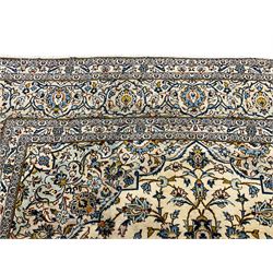 Persian Kashan golden ivory ground carpet, the central medallion surrounded by a field of interlacing branch and stylised plant motifs, the guarded border with scrolling design decorated with flower heads 
