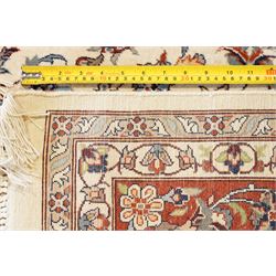 Persian ivory ground Kashan carpet, the busy field decorated with a central floral pole medallion with matching spandrels, the field profusely decorated with scrolling foliate motifs, the crimson guard stripe with repeating scrolling palmettes