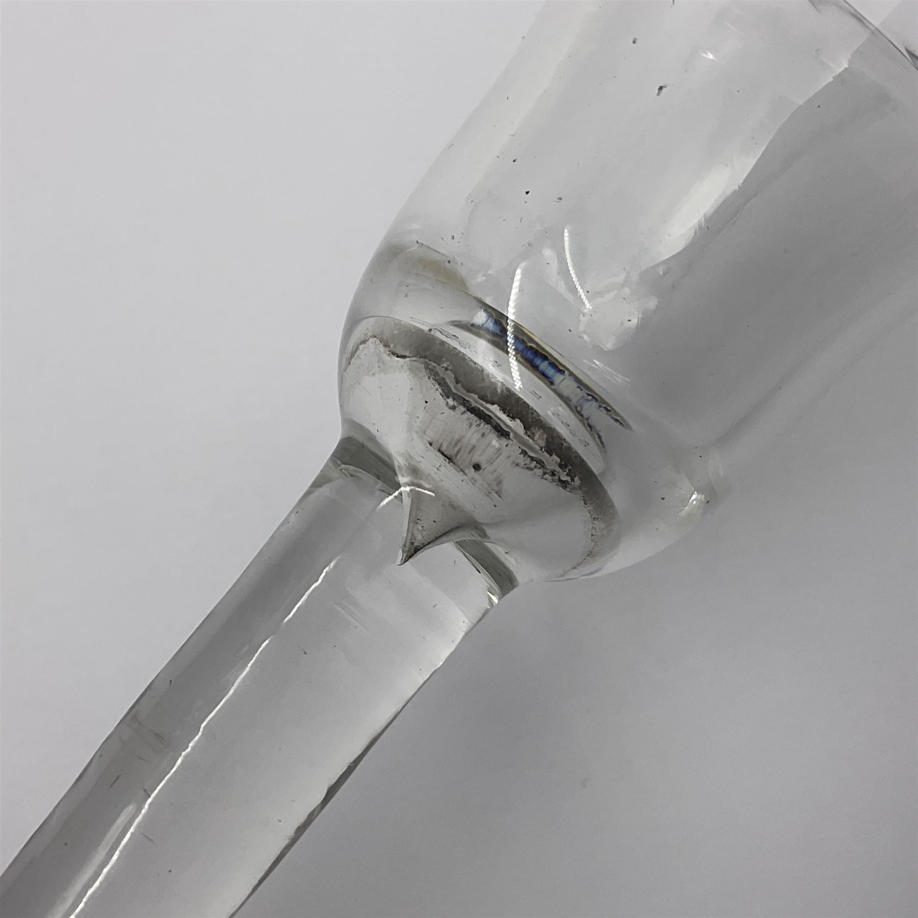 Three 18th century wine glasses comprising a plain stemmed glass with bell shaped bowl and conical folded foot H16cm, another plain stemmed glass with ogee bowl and folded foot and a Continental glass with gilt faceted bowl, decorated with male figure within a landscape, on a clear Silesian seven sided cut stem (3)