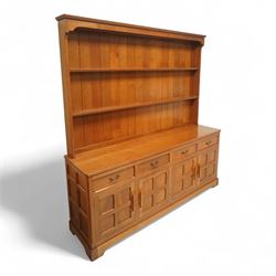 Seahorseman by Shaw & Riley - Yorkshire oak Welsh dresser, the dresser rack of rectilinear form with plain frieze and projecting moulded edge above two shelves with central shallow groove, the base section fitted with four drawers and a fitted cutlery drawer containing cutlery, above four panelled cupboard doors with geometric mouldings and carved sculpted handles, interior with single shelf and sides with geometric mouldings raised on a shallow plinth base with shaped bracket feet, with signature Seahorse carving from the workshop from the workshop of A. Shaw & Riley Ltd, Hessay