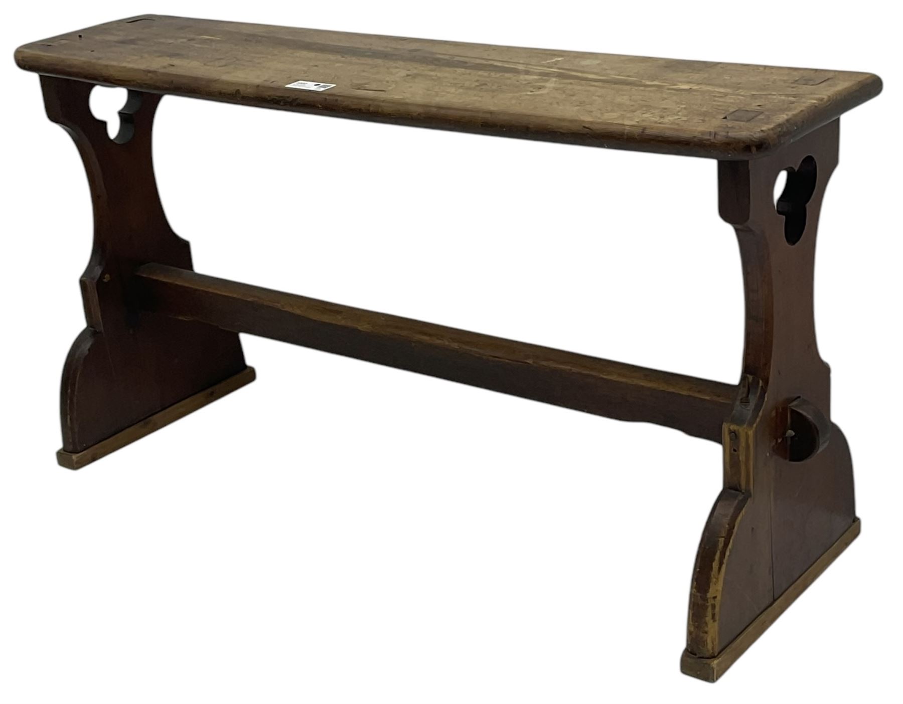 Late Victorian ecclesiastical pitch pine side table, rectangular bow-front top, on shaped end supports pierced with quatrefoils, united by pegged stretcher 