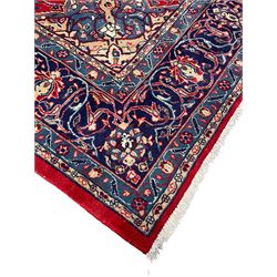 Kashan crimson ground carpet, overall floral design, the central medallion surrounded by trailing leafy branches and palmettes, scrolling border decorated with stylised plant motifs, within guard stripes