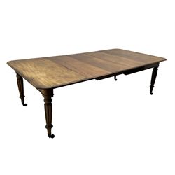 Early 19th century figured mahogany extending dining table, the rectangular top with moulded edge and rounded corners, pull-out action with three additional leaves, raised on turned and lobe carved supports with brass cup castors