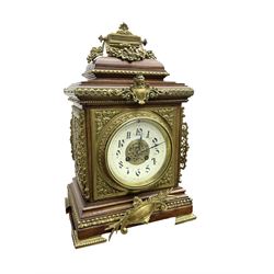 French - Early 20th century 8-day mantle clock in an oak case with pierced brass frets to the sides and raised on bracket feet, enamel dial with brass spandrels, Arabic numerals and a pierced centre, Two train rack striking movement, striking the hours and half-hours on a coiled gong. With pendulum and key. 