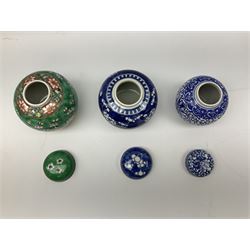 Six Chinese ginger jars, predominantly of blue and white design decorated with blossoming branches, all with lids, housed on various hardwood carved stands, some with character marks beneath